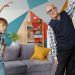 Retired grandfather and cute child do physical exercises together in house working out indoors caring for health. Healthy lifestyle and activity concept.