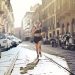 Energetic woman jogger running down a city street in active wear on a sunny day.